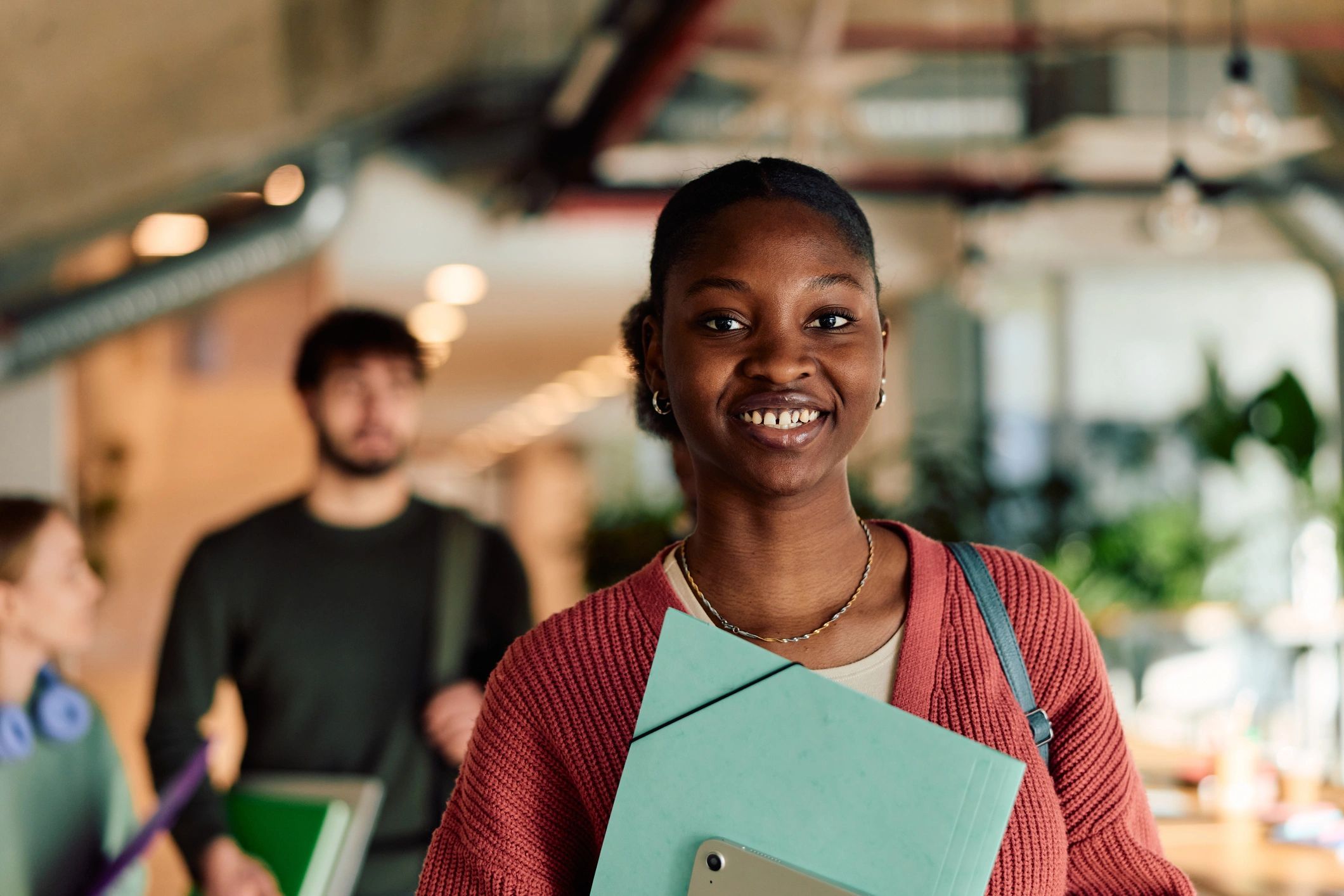 Happy student smiling with folder and tablet